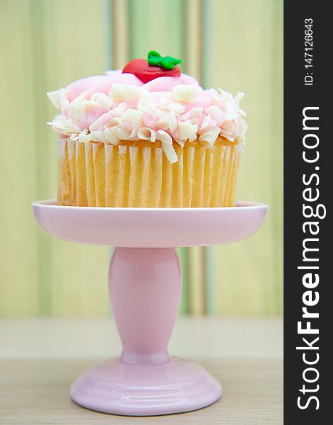 Strawberry cupcake with pink frosting on a dessert display stand pillar pedestal