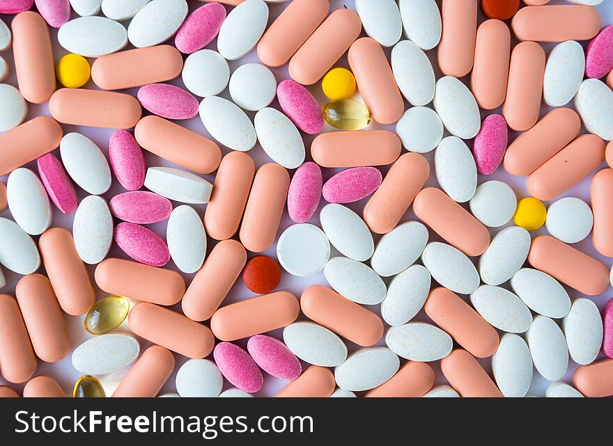 Many pills and drugs in bright colors on white background