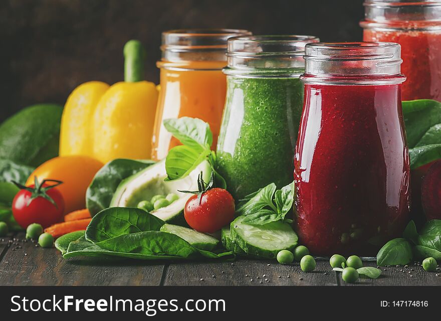 Colorful vegetable juices and smoothies from tomato, carrot, pepper, cabbage, spinach, beetroot in bottles on kitchen table, vegan