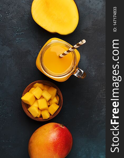 Mango smoothie in glass jar with fresh fruit on blue background, copy space, top   view