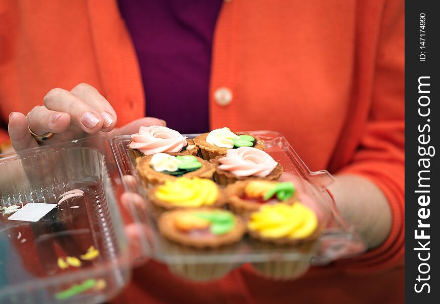 Female hands holding a plastic box with brownies, indoor close-up. Female hands holding a plastic box with brownies, indoor close-up