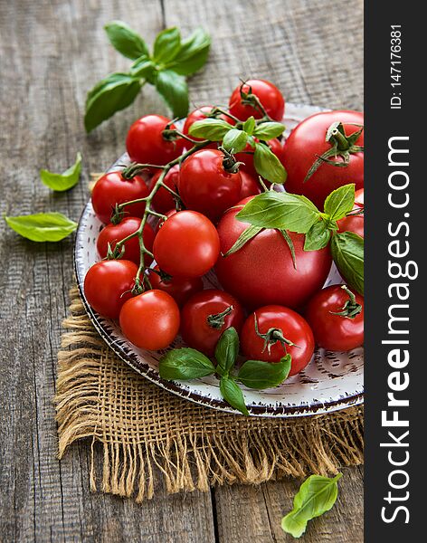 Plate with tomatoes and green basil on a wooden table