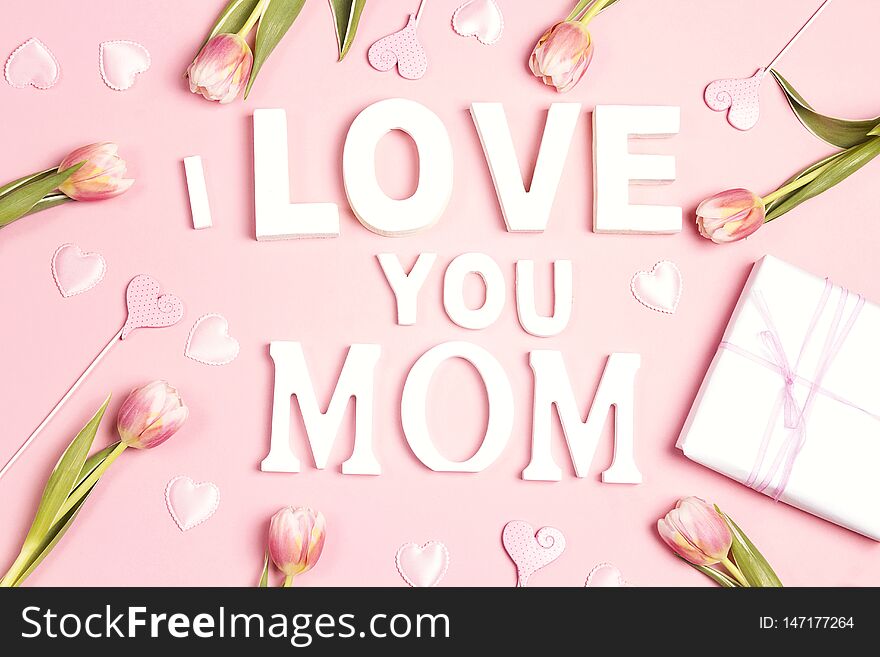 Mothers day message with tulips and hearts on pink background. Flat lay, top view
