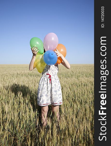 Girl with balloons at wheat field.