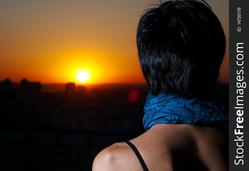 Girl from back looks on sunset from cities roof. Girl from back looks on sunset from cities roof