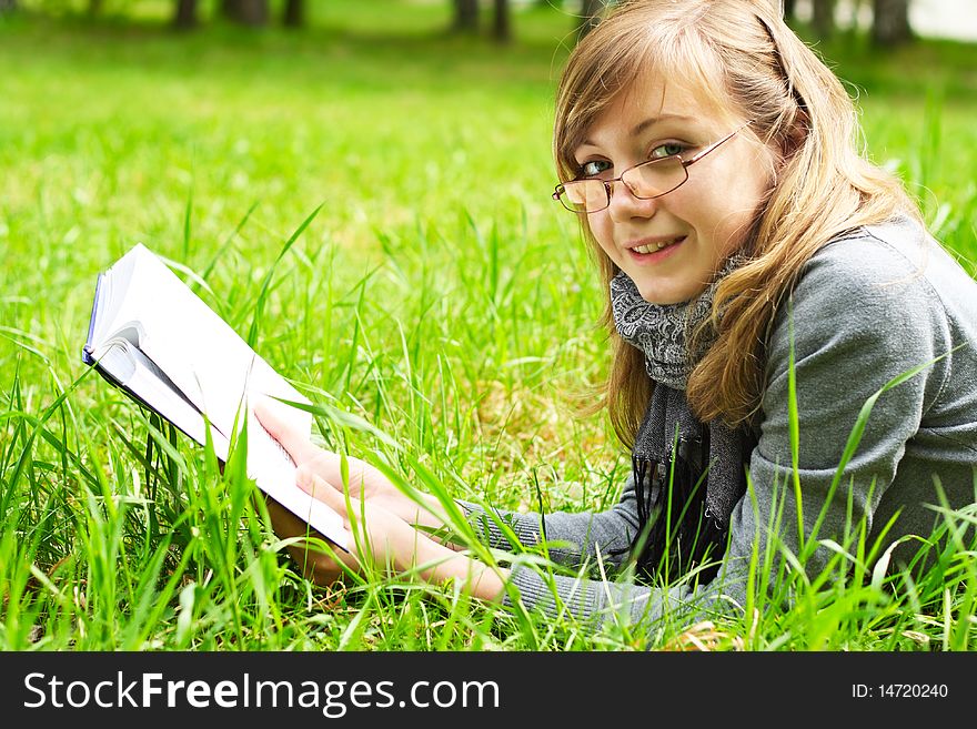 The girl lays on a green grass, and reads the book. The girl lays on a green grass, and reads the book