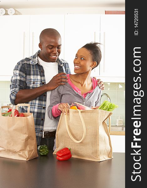 Young Couple Unpacking Shopping In Kitchen