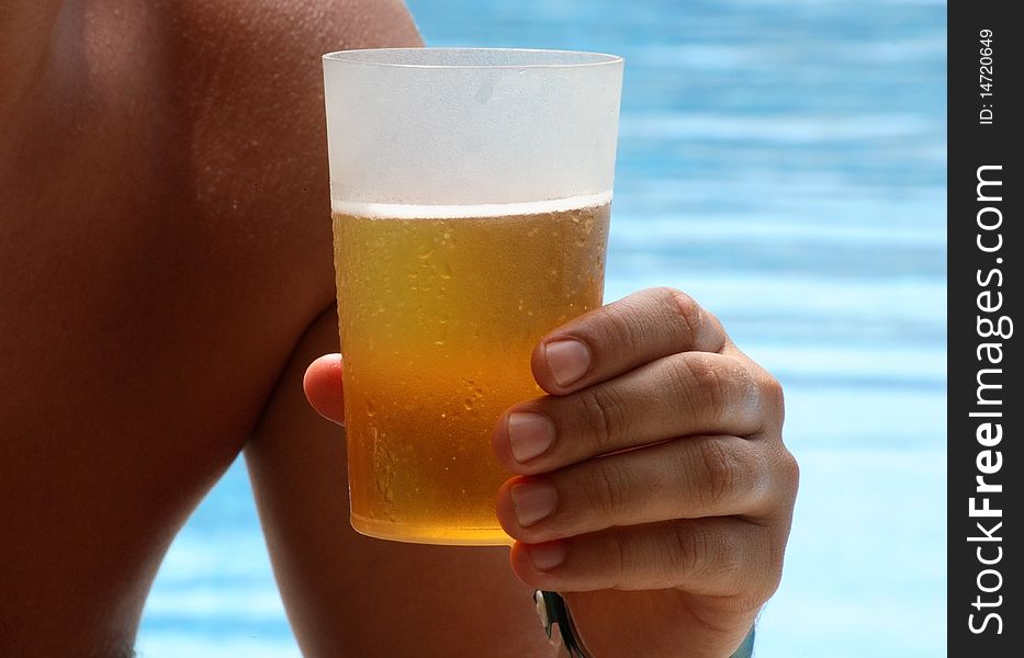 Man holding a beer glass, water background, outdoor