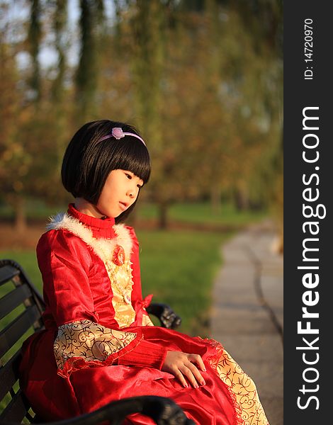The little Chinese girl sitting on the bench. The little Chinese girl sitting on the bench