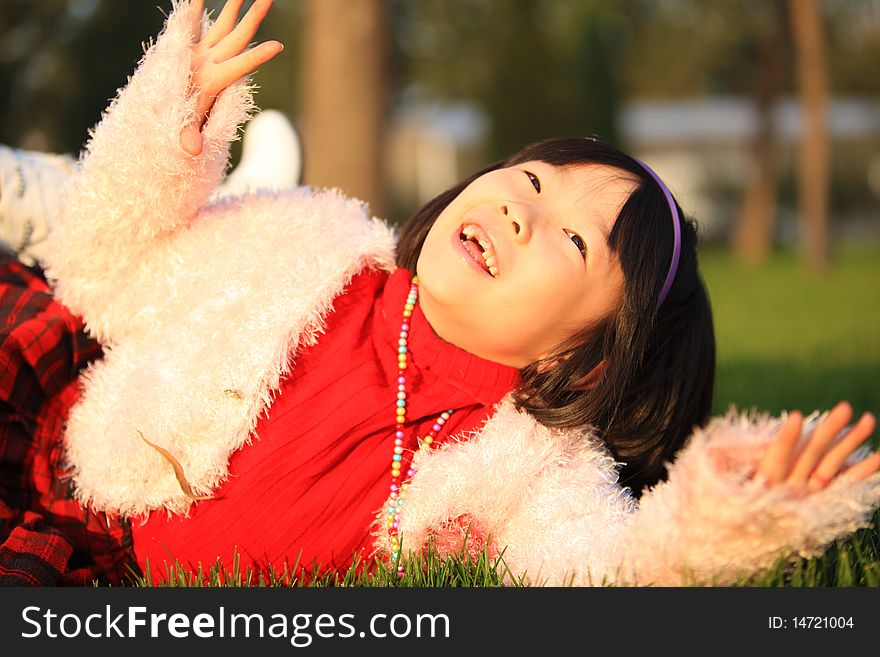 The little Chinese girl laughing on the grass in autumn. The little Chinese girl laughing on the grass in autumn