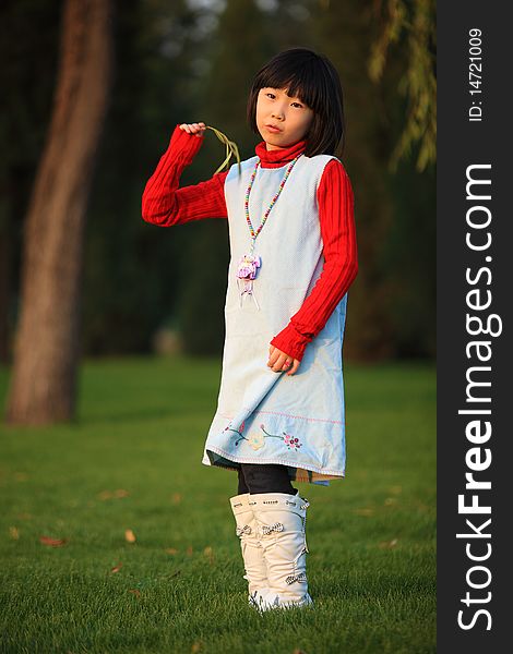 The little Chinese girl standing outside in autumn. The little Chinese girl standing outside in autumn