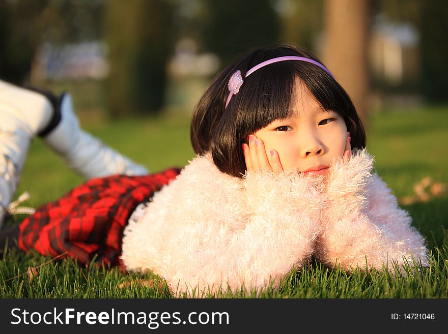 The little Chinese girl lying on the grass in autumn. The little Chinese girl lying on the grass in autumn