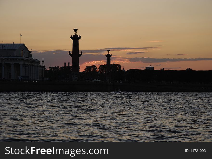 White Nights of Saint-Petersburg. Russia.  View of the Neva river and silhouettes of Rostral Columns on Vasilyevsky island. White Nights of Saint-Petersburg. Russia.  View of the Neva river and silhouettes of Rostral Columns on Vasilyevsky island.