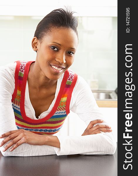 Young Woman Relaxing In Modern Kitchen Smiling At Camera