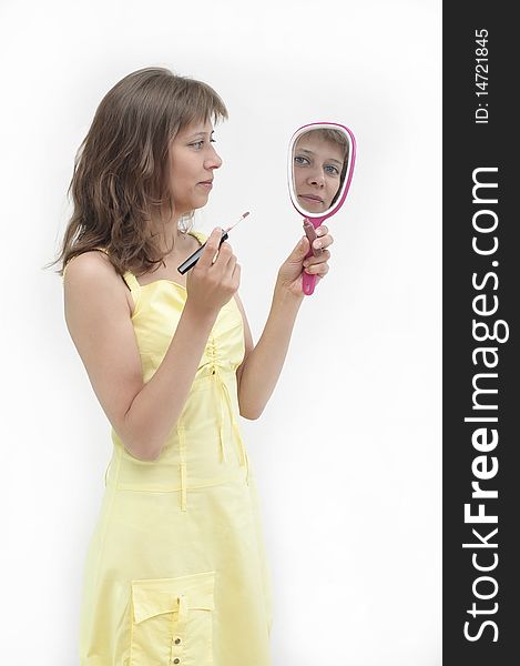 The young woman looks in a mirror and paints lips