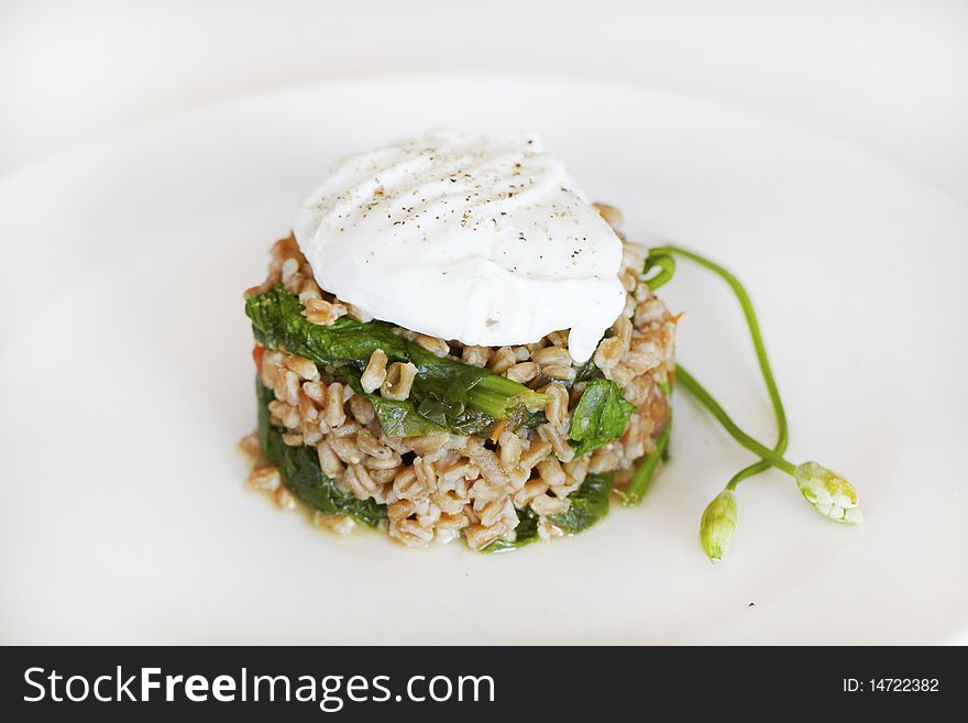 Poached egg on wheat grains with spinach