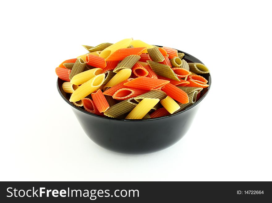 Raw colored pasta in black bowl isolated on white background