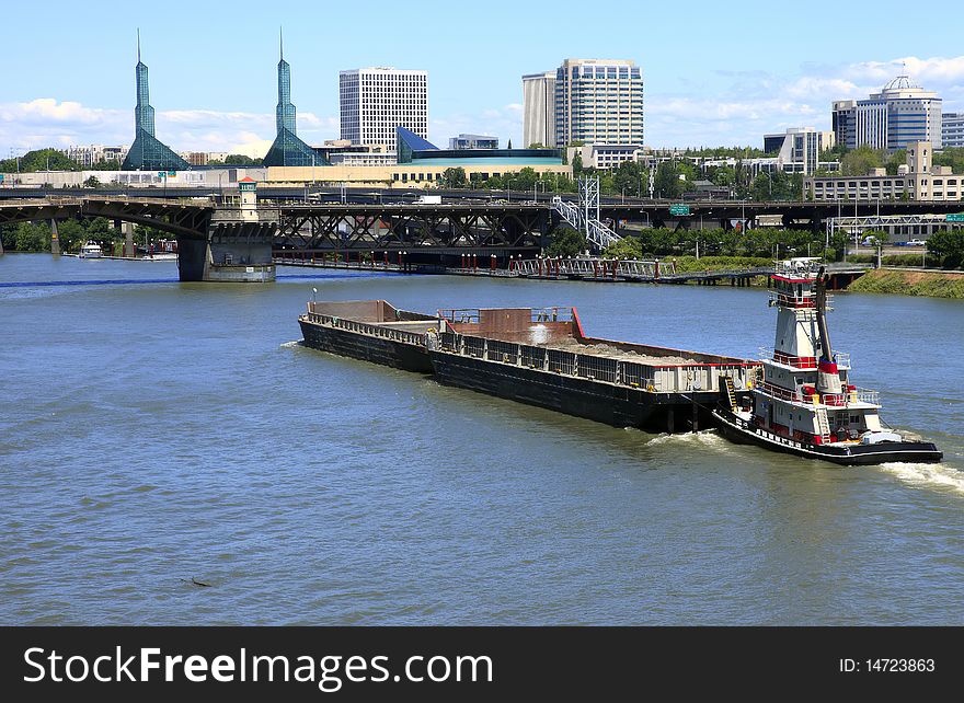 A push boat and barges traveling on the Willamette river through bridges near downtown Portland Oregon. A push boat and barges traveling on the Willamette river through bridges near downtown Portland Oregon.