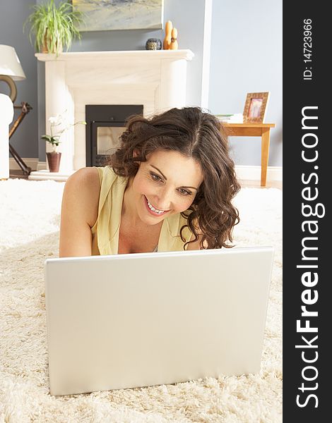 Woman Using Laptop Relaxing Laying On Rug At Home Smiling