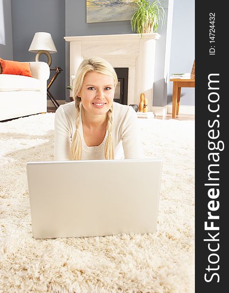 Woman Using Laptop Relaxing Laying On Rug At Home Smiling At Camera