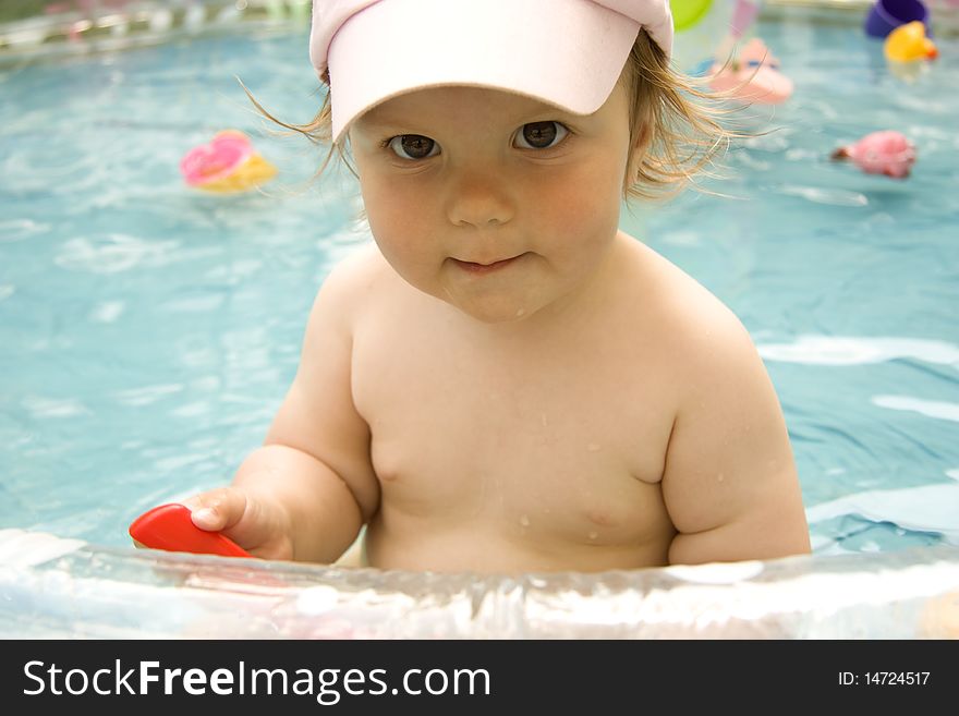The beautiful child in a cap with the big eyes sits in pool. The beautiful child in a cap with the big eyes sits in pool