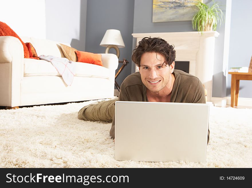 Man Using Laptop Relaxing Sitting On Rug At Home