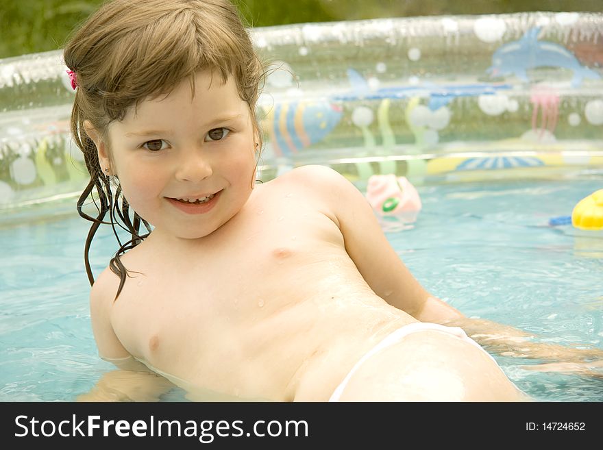 The girl sits in the summer on the nature in pool and looks directly. The girl sits in the summer on the nature in pool and looks directly