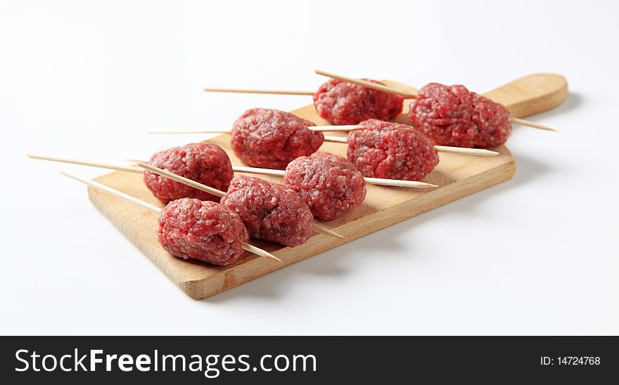 Raw minced meat balls on skewers - studio