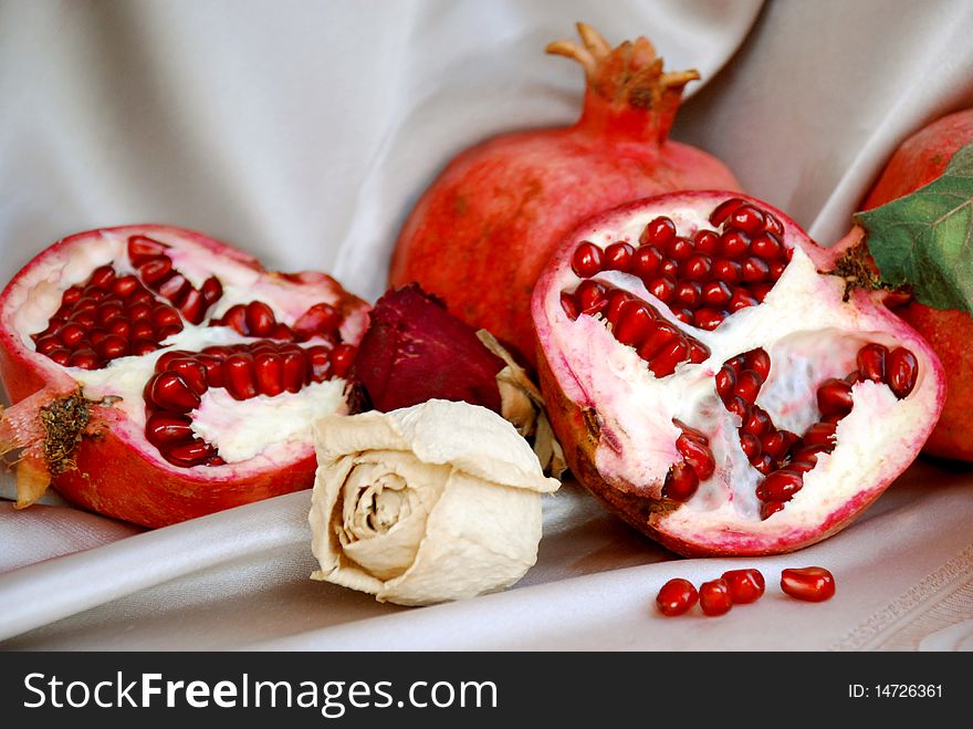 Pomegranates whole and seeded with dry roses