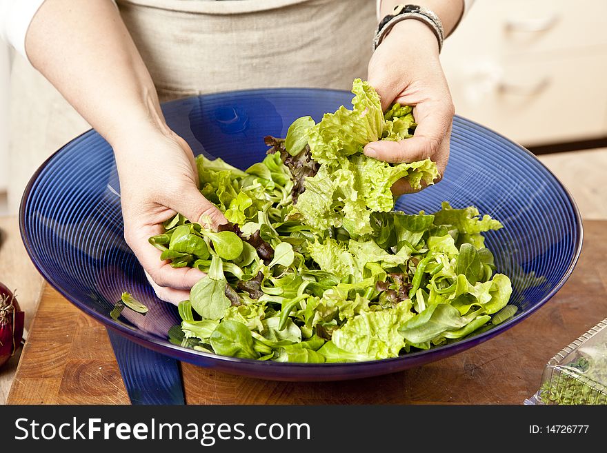 Chef mixing a salad of various sorts of lettuce in a blue bowl. Chef mixing a salad of various sorts of lettuce in a blue bowl