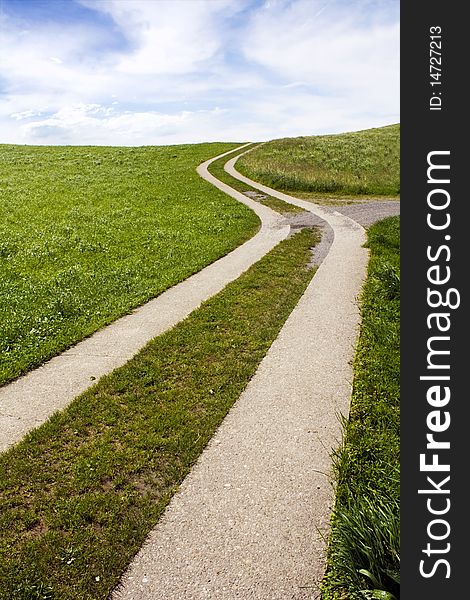 Snaky path in the green grass with nice cloudy sky in back. Snaky path in the green grass with nice cloudy sky in back