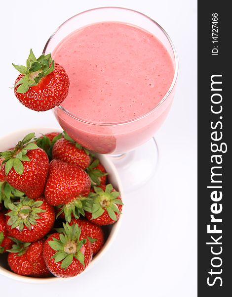 Strawberries in a bowl and a strawberry shake in a glass decorated with a strawberry on white background. Strawberries in a bowl and a strawberry shake in a glass decorated with a strawberry on white background