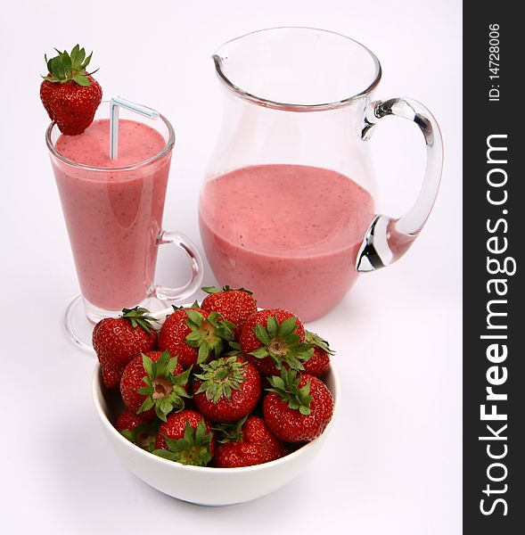 Strawberries in a bowl and a strawberry shake in a glass with a straw and in a jug on white background. Strawberries in a bowl and a strawberry shake in a glass with a straw and in a jug on white background