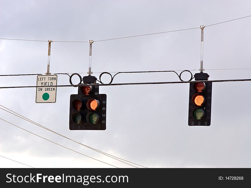 Traffic stoplights suspended over road, the signal is yellow and means yield, proceed with caution. Traffic stoplights suspended over road, the signal is yellow and means yield, proceed with caution.