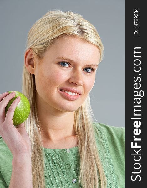 Woman Relaxing On Sofa Eating Apple At Home Smiling At Camera