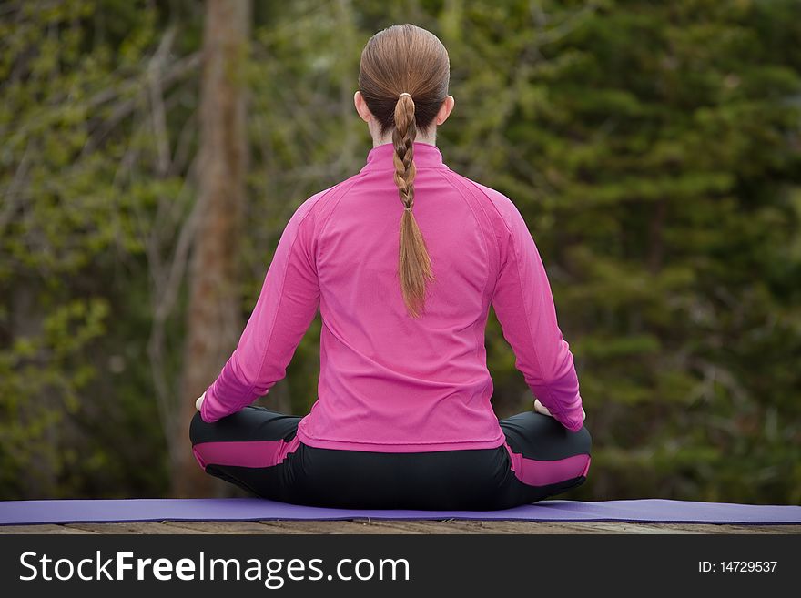 Athletic woman sitting on a yoga mat meditating in a forest. Athletic woman sitting on a yoga mat meditating in a forest.