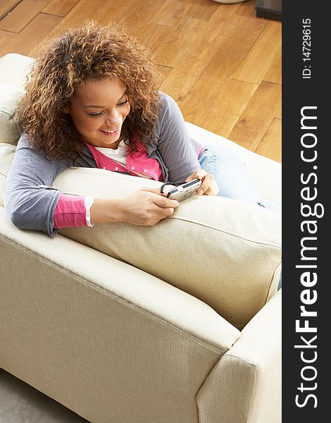 Woman Looking At Pictures On Digital Camera Relaxing Sitting On Sofa At Home