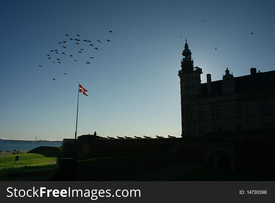 Helsingor Kronborg castle in sunrise with historical canon guns and denmark flag