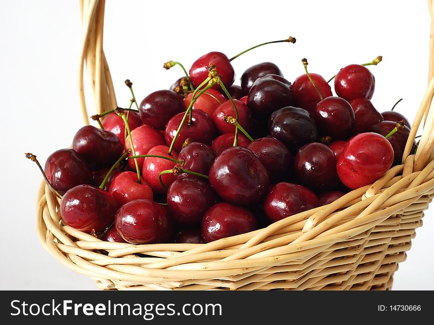 Wicker basket with fresh red cherries on the white background. Wicker basket with fresh red cherries on the white background