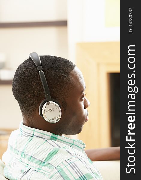 Young Man Relaxing Sitting On Sofa Listening to Music At Home On Headphones