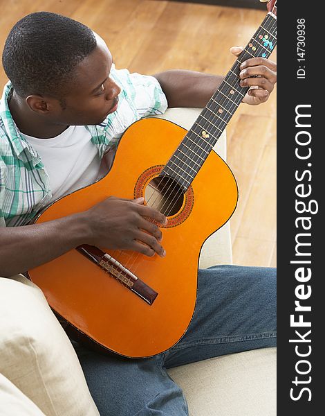 Man Relaxing Sitting On Sofa Playing Guitar