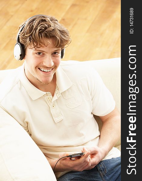 Man Listening To MP3 Player On Headphones Relaxing Laying On Rug At Home