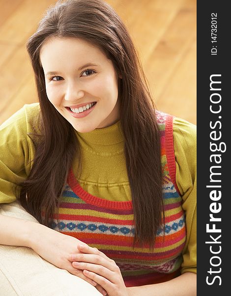 Woman Relaxing On Sofa At Home Smiling At Camera