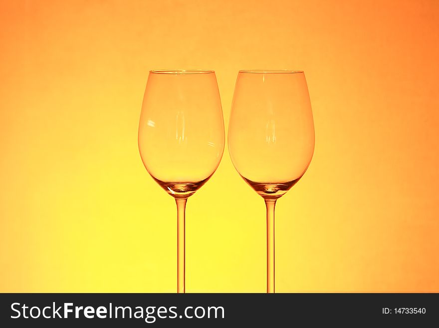 Two empty wineglasses isolated on gradient yellow background