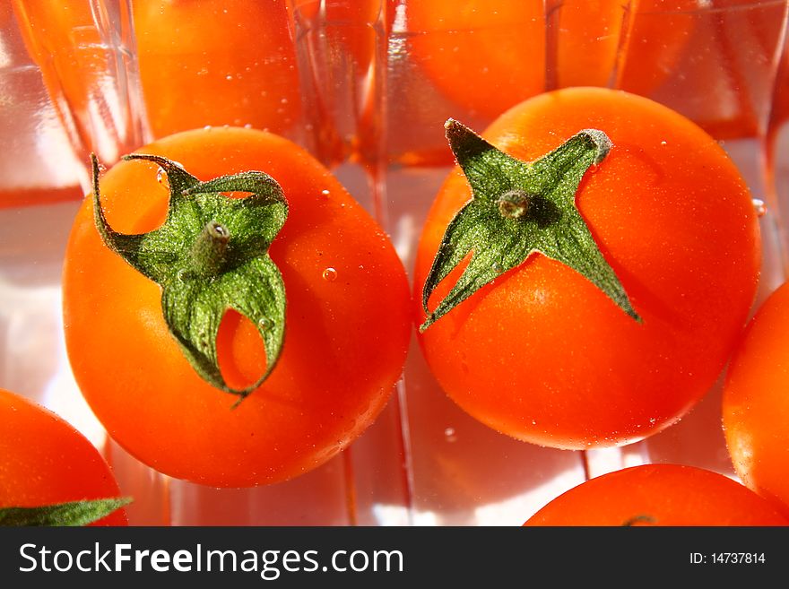 Close-up of two small cherry tomatoes sitting in a plastic tray viewed from above. Close-up of two small cherry tomatoes sitting in a plastic tray viewed from above.