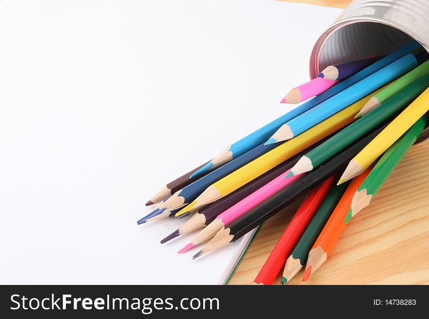 Wooden pencils of different colour on a white paper.