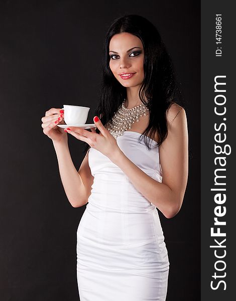 Beautiful young woman with a cup isolated on black
