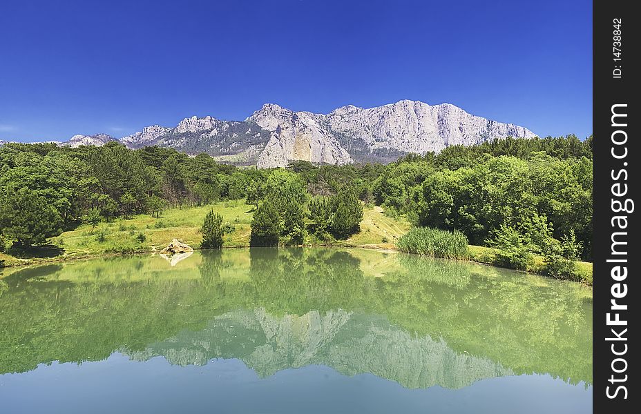 Landscape from mountains and wood is reflected in lake. Landscape from mountains and wood is reflected in lake
