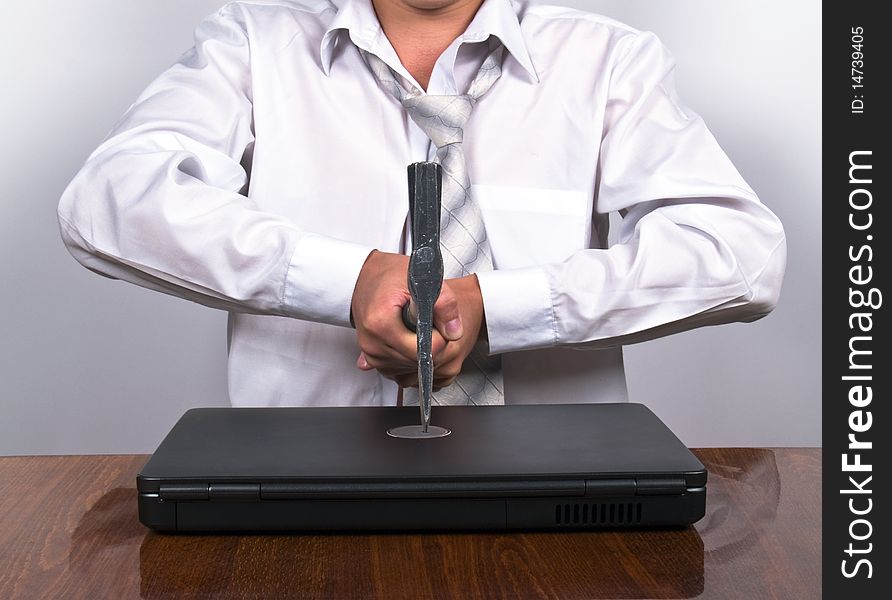 Businessman sitting in the office holding axe cutting up laptop. Businessman sitting in the office holding axe cutting up laptop