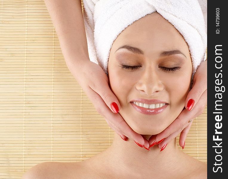 Portrait of a young and beautiful brunette on a spa treatment procedure. Image taken on a bamboo background.